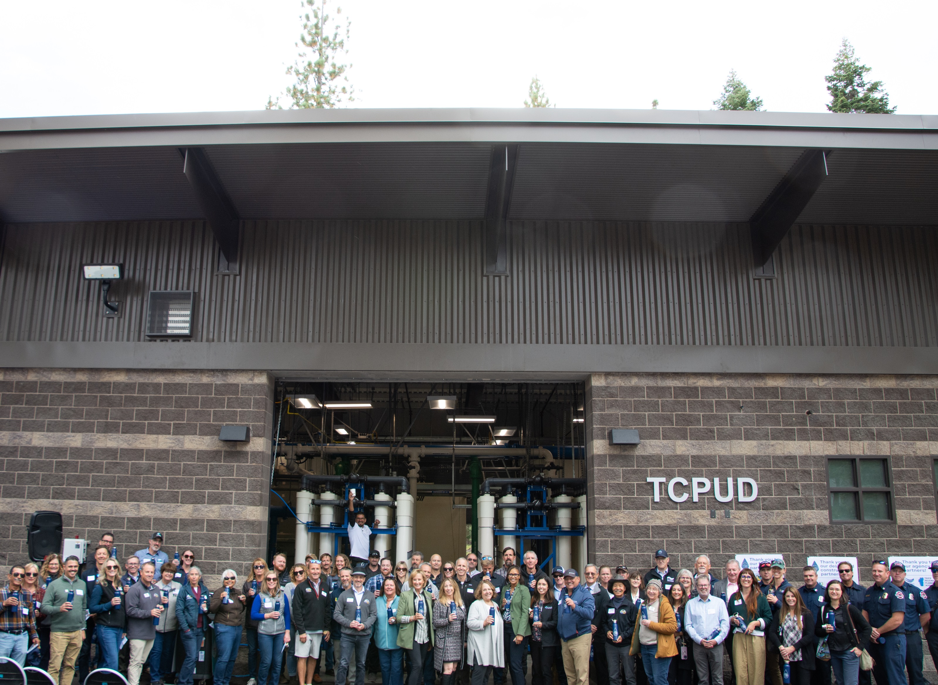 Group photo of grand opening attendees in front of the water treatment plant building.